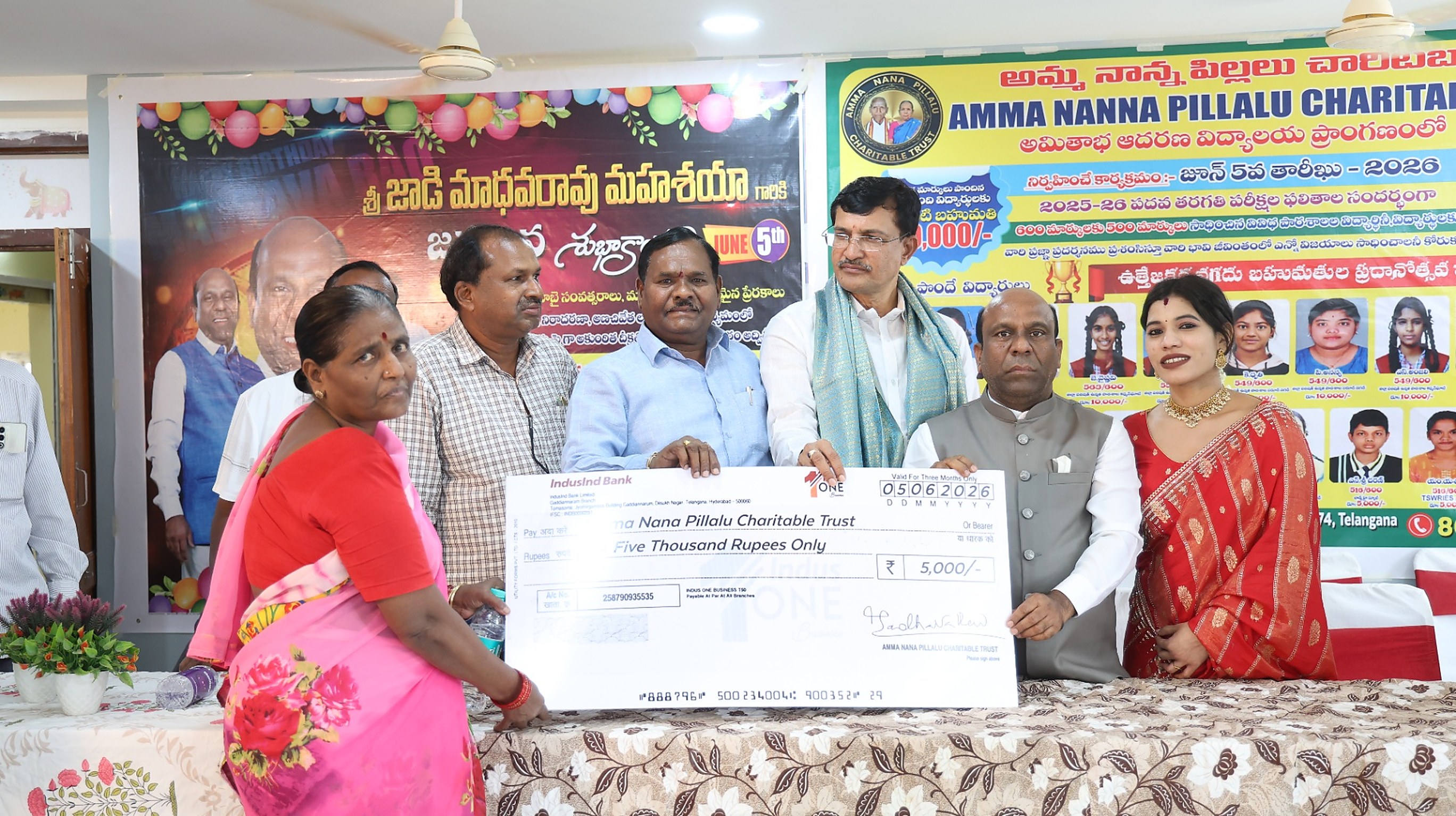 Parent and student receiving a ₹5,000 scholarship cheque on stage